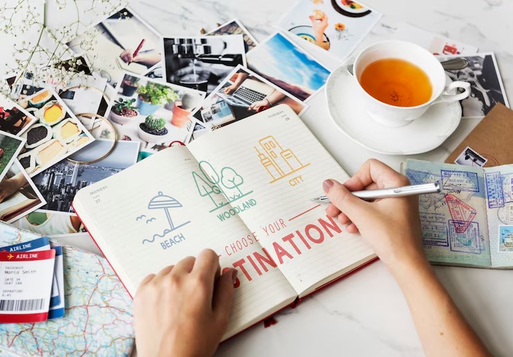 Woman's hand writing in a notebook, noting down a travel destination with a pen