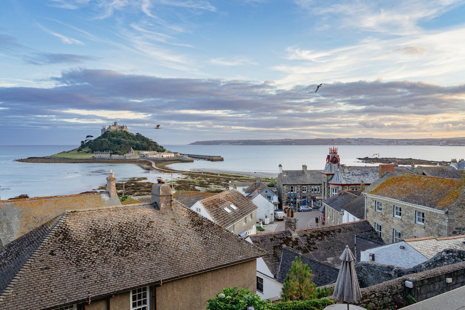 A scenic view of a town with a historic castle prominently situated in the background against a clear sky